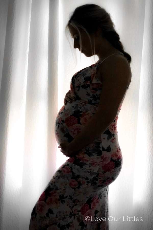 A silhouette maternity photo in front of a window.