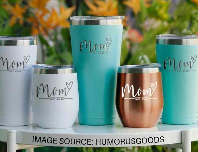 Photo of 5 stainless steel tumblers in green, white and gold that say mom with a heart.