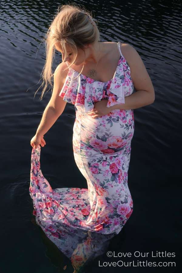 Pregnant woman taking a maternity photo in the water during sunset.