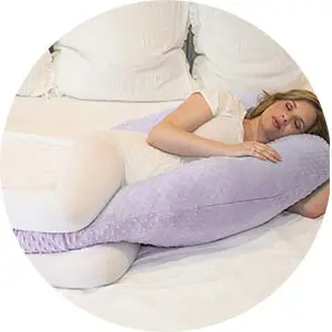 pregnant woman lying on the bed with her purple minky pregnancy pillow.