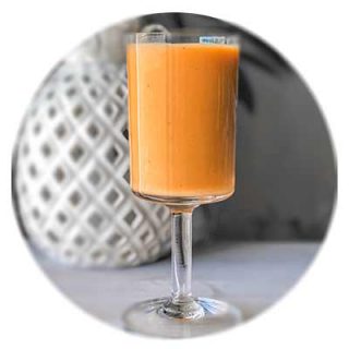 An orange smoothie in a stem glass.