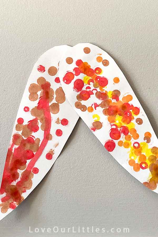 Two corn cob shaped papers with red, orange and yellow dots.