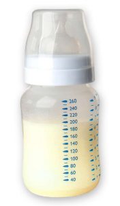 A baby bottle filled with yellow colored breast milk.